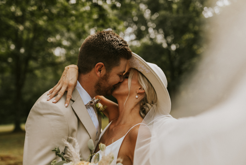 That just married feeling from bride and groom. Bride wearing a beautiful boho and trendy hat. Bridal photos in brides backyard.